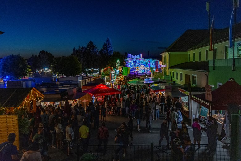 Das Bild zeigt die Verpflegungs- und Vergnügungsmeile des Rehauer Wiesenfests vom Festzelt kommend. Zu sehen sind viele Besucher und Anbieter.