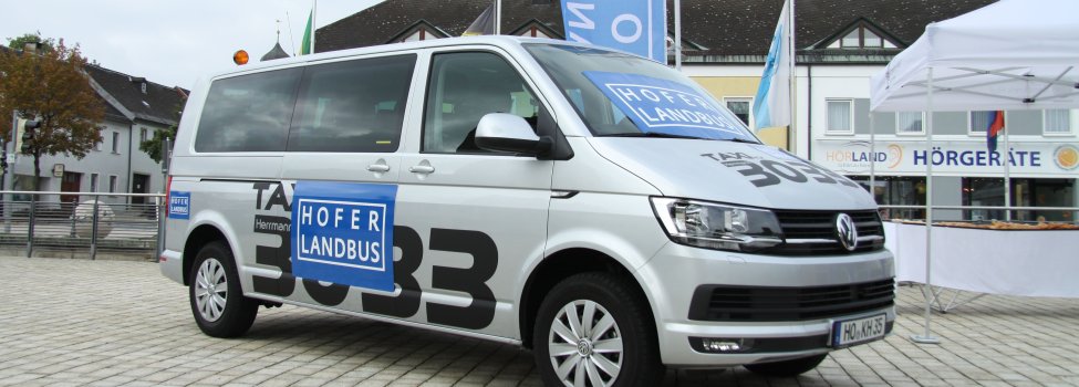 Das Bild zeigt den Hofer Landbus. Konkret handelt es sich um einen VW Bus mit der Aufschrift "Taxi 3033" und den blauen Hinweistafeln "Hofer Landbus"