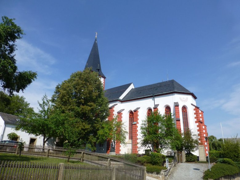 Das Bild zeigt die Pilgramsreuther Kirche von außen. Es handelte sich um ein Bild aus dem Sommer, weil die daneben befindlichen Bäume und Büsche sehr grün erscheinen.