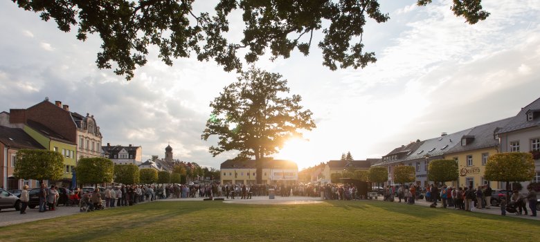 Das Bild zeigt viele Personen bei einer Veranstaltung am Maxplatz. Die Sonne ist kurz vor dem Verschwinden. Zu sehen sind in der Mitte des Maxplatzes einige Musiker.