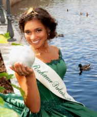 Das Bild zeigt die derzeitige Perlenkönigin Katherina I. in ihrem grünen Kleid und einer Perle in der Hand.
