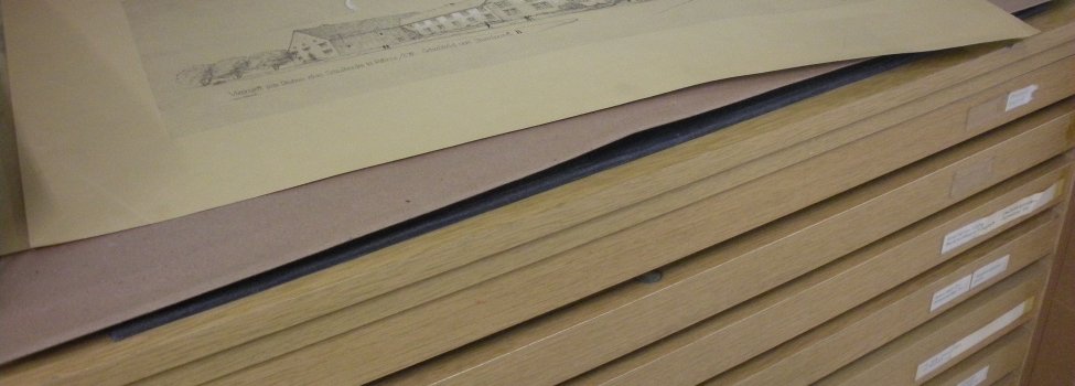 Das Bild ist im Rehauer Stadtarchiv aufgenommen und zeigt eine Skizze auf einem Schrank mit einigen Schubladen.