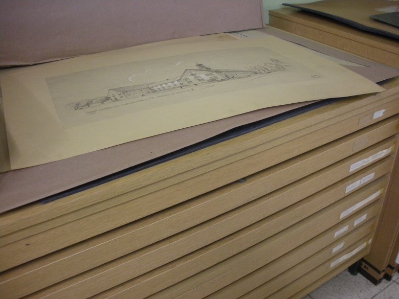 Das Bild ist im Rehauer Stadtarchiv aufgenommen und zeigt eine Skizze auf einem Schrank mit einigen Schubladen.