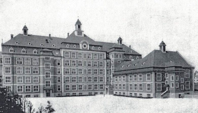 Das schwarz-weiß Foto zeigt ein großes Gebäude mit vielen Fenstern und einem Innenhof.