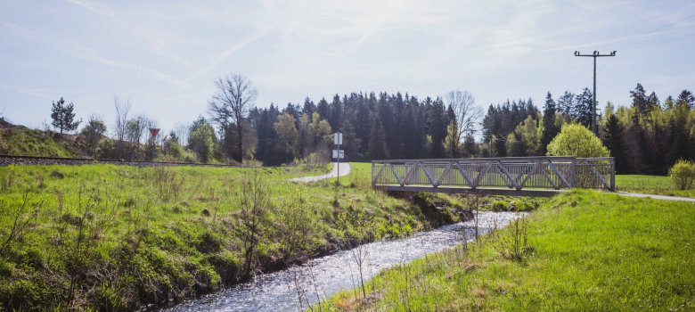 Das Bild zeigt den Serpentinit-Rundwanderweg Wurlitz/Woja: Der Weg verläuft über eine Brücke neben der Bahnstrecke.